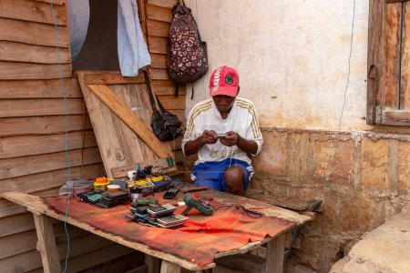 Foto de Miandrivazo, Madagascar - 2 de noviembre de 2022: El hombre malgache trabaja en la reparación de teléfonos en la calle Miandrivazo, una ciudad en la región de Menabe en Madagascar. - Imagen libre de derechos