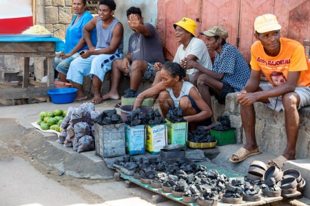 Foto de Miandrivazo, Madagascar - 2 de noviembre de 2022: Mercado callejero en Miandrivazo, mujer que vende carbón. El carbón vegetal de madera se utiliza principalmente para cocinar en Madagascar. - Imagen libre de derechos
