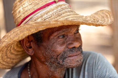 Foto de Miandrivazo, Madagascar - 2 de noviembre de 2022 - Anciano con sombrero de paja y sonrisa. Hombre mayor descansando en la calle. - Imagen libre de derechos