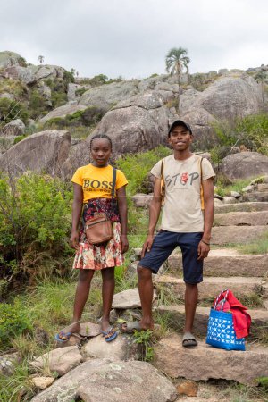 Téléchargez les photos : Andringitra, Madagascar - 16 novembre 2022 : Jeune homme et jeune femme debout sur un sentier rocheux dans une région montagneuse. Jeune couple marchant sur un sentier rocheux dans une région montagneuse portant des tongs. - en image libre de droit
