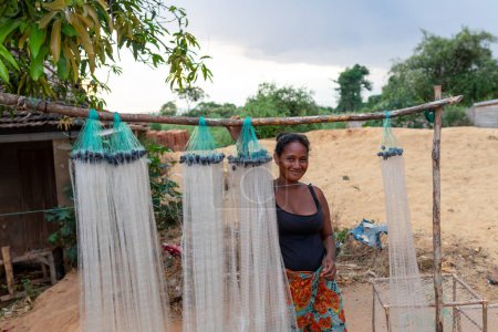 Foto de Miandrivazo, Madagascar - 1 de noviembre de 2022: Una mujer malgache que vende redes de pesca colgadas de un palo de madera. - Imagen libre de derechos