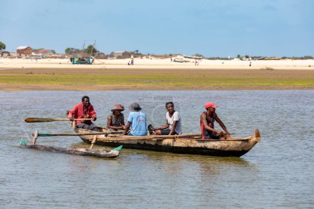 Téléchargez les photos : MORONDAVA, MADAGASCAR - 22 NOVEMBRE 2022 : Famille malgache en bateau traditionnel en bois traversant la rivière Morondava, Madagascar. - en image libre de droit