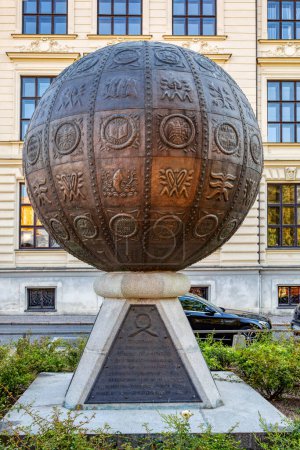 Foto de Litomysl, República Checa, 29 de septiembre de 2023: Monumento inusual en forma de bola de metal con imágenes en relieve frente al edificio histórico Escuela Pedagógica Profesional Superior. - Imagen libre de derechos