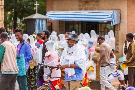Bahir Dar, Ethiopia - April 21st, 2019: Orthodox Christian people white dressed walk to mass on the street during Easter holiday reflecting the traditions and festive atmosphere of the occasion.