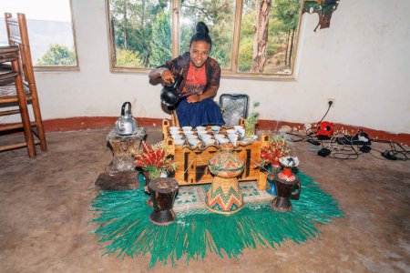 Photo for Debre Libanos, Ethiopia - April 27, 2019: Woman perform a traditional Ethiopian coffee ceremony, preparing street bunna coffee. - Royalty Free Image