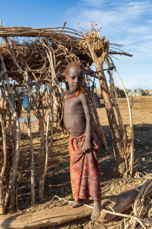 Photo for Omorate, Omo Valley, Ethiopia - May 11, 2019: Children from the African tribe Dasanesh in village. Daasanach are Cushitic ethnic group inhabiting in Ethiopia, Kenya, and South Sudan - Royalty Free Image