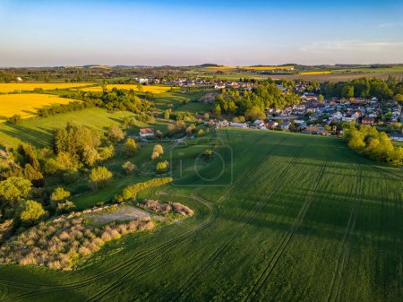 Drone survole la campagne avec un champ de blé vert. Région montagneuse avec forêt. Jour de printemps chaud et ensoleillé. Vue aérienne paysage. Beau paysage rural. République tchèque