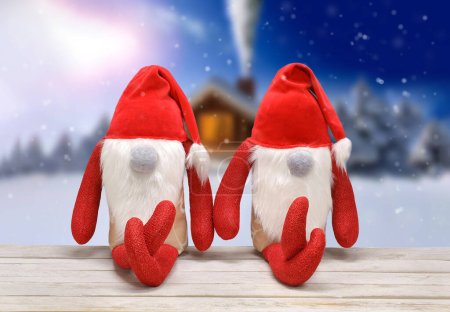 Photo for Two Christmas Elves are sitting on a bench, textile toys, winter landscape in the background and empty space for tex - Royalty Free Image