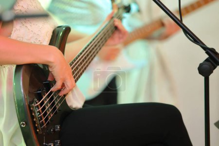 Photo for Closeup of a woman's hand playing the bass guitar at a concer - Royalty Free Image