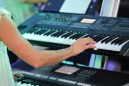 Photo for Closeup of a woman's hand playing a double keyboard at a concert - Royalty Free Image