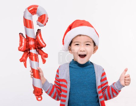 Téléchargez les photos : Joyeux petit garçon habillé en chapeau de Noël Père Noël et tenant cadeau - en image libre de droit