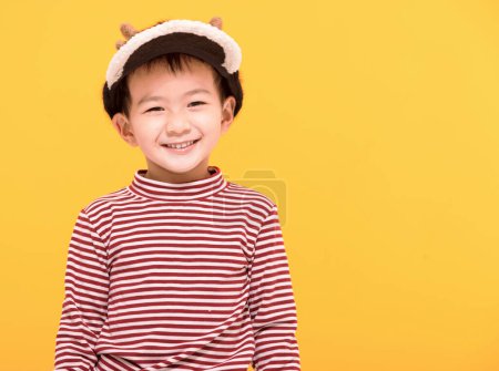 Téléchargez les photos : Enfant heureux habillé en chapeau de Noël et regardant la caméra - en image libre de droit