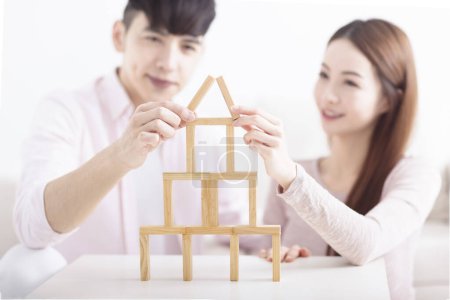 Foto de Feliz joven pareja construyendo casa con ladrillos de madera para el concepto de hogar - Imagen libre de derechos