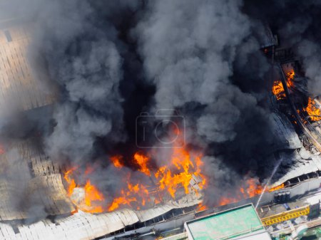 Téléchargez les photos : Vue aérienne du feu dans un bâtiment industriel. hangar en béton de plusieurs étages avec des flammes. Concept d'urgence usine. - en image libre de droit