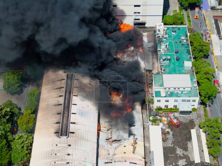 Foto de Vista aérea de Fuego en edificio industrial. hangar de hormigón de varios pisos con llamas. Concepto de emergencia. - Imagen libre de derechos