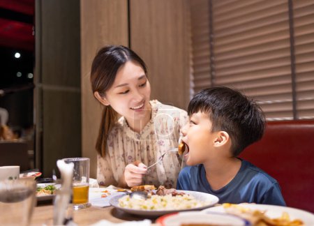 Photo for Happy mother feeds her son in restaurant - Royalty Free Image