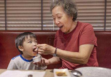 Photo for Happy grandmother feeds her grandson in restaurant - Royalty Free Image