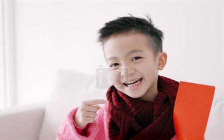 Foto de Feliz chico asiático mostrando y sosteniendo sobre rojo. Feliz año nuevo chino concepto. - Imagen libre de derechos