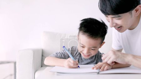 Foto de Young father checking homework helping  child  with study at home - Imagen libre de derechos