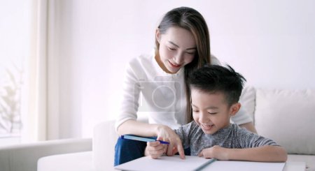 Photo for Young mother checking homework helping  child  with study at home - Royalty Free Image