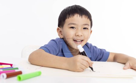 Foto de Sonriente asiático niño escolar estudiar y dibujo en casa - Imagen libre de derechos