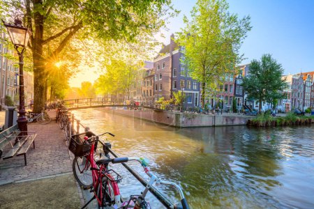 Photo for Soul of Amsterdam. Early morning in Amsterdam. Ancient houses, a bridge, traditional bicycles, canals and the sun shines through the trees. Great day in Amsterdam. Holland, Netherlands, Europe. - Royalty Free Image