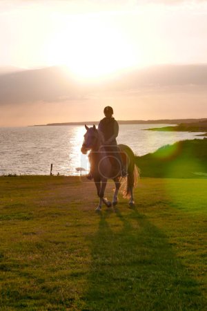 Téléchargez les photos : Coucher de soleil Équitation sur la plage avec l'océan en arrière-plan. - en image libre de droit