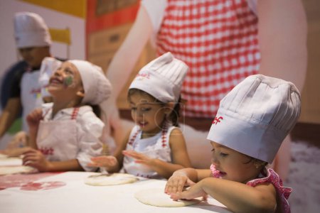 Foto de MEDELLIN, COLOMBIA, 15 DE MARZO: Un grupo de niñas que trabajan en pasteles en la cocina. Colombia 2015 - Imagen libre de derechos