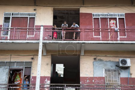 Foto de CIUDAD DE PANAMÁ, PANAMÁ, 3 DE MARZO DE 2014: Un pequeño grupo de adolescentes de pie junto a la terraza en un edificio pobre en la ciudad de Panamá. - Imagen libre de derechos