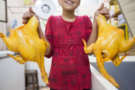 Foto de Tupiza, Bolivia - 30 de diciembre de 2014: Joven asiática sonriendo y sosteniendo dos pollos a la venta dentro de una tienda local en Tupiza, Bolivia - Imagen libre de derechos