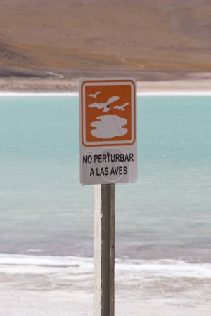 Foto de Señal de advertencia con el lago volcánico en el Parque Nacional Eduardo Avaroa en Bolivia. - Imagen libre de derechos