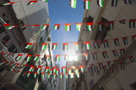 Foto de Pequeños buntings de banderas de los Emiratos Árabes Unidos exhibidos sobre edificios antiguos en Bur Dubai. - Imagen libre de derechos
