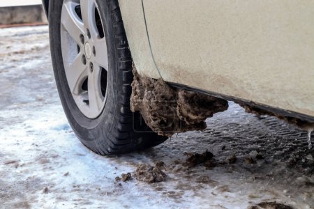 Téléchargez les photos : Wet dirty snow stuck to the car. Mud covered salty gray car close-up - en image libre de droit