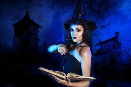 Photo for Half length portrait of beautifull young woman in witch dress holding magic wand standing next to color background - Royalty Free Image