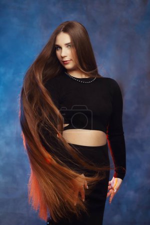 Chica con natural crecido propio cabello sobre fondo azul con luz de fondo naranja