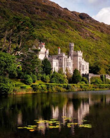 Téléchargez les photos : Abbaye de Kylemore parmi les verts dans les montagnes du Connemara avec réflexion dans le lac - en image libre de droit