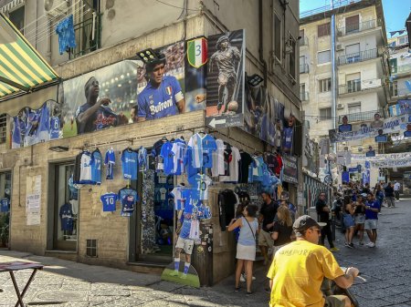 Foto de Nápoles, Italia, 27 de septiembre de 2023: El barrio de Quartieri Spagnoli en Nápoles con un mural de Diego Armando Maradona y un gran número de tiendas relacionadas con el fútbol y el club Napoli. - Imagen libre de derechos
