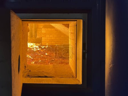 Burning coal and slag on a mechanical grate visible through the open hatch of a coal-fired grate boiler.