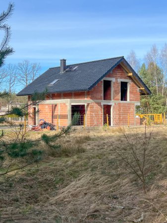 Ein Einfamilienhaus aus Keramikblöcken mit Ziegeldach, ohne Fenster und Türen, im Rohbauzustand.