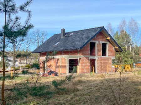 Ein Einfamilienhaus aus Keramikblöcken mit Ziegeldach, ohne Fenster und Türen, im Rohbauzustand.