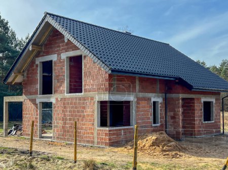 Une maison unifamiliale construite en blocs de céramique avec un toit en tuiles, sans fenêtres et portes, à l'état de coquille.