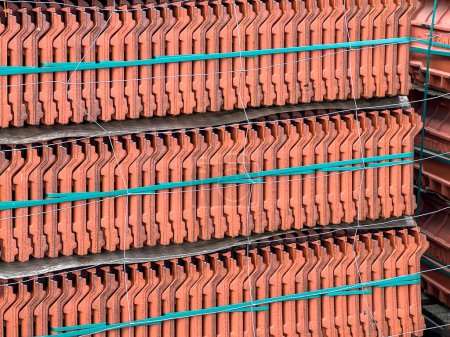 Roof tiles stacked on a pallet, visible from the side as a background.