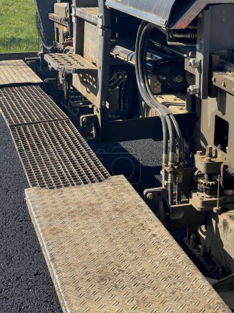 Construcción de una nueva superficie de calle. Colocar una capa de asfalto con una máquina especializada. Fragmento de una máquina de asfalto.
