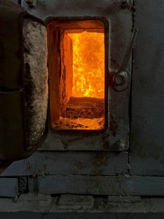 Fuego en la cámara de combustión de una estufa de carbón visible a través de la ventana.