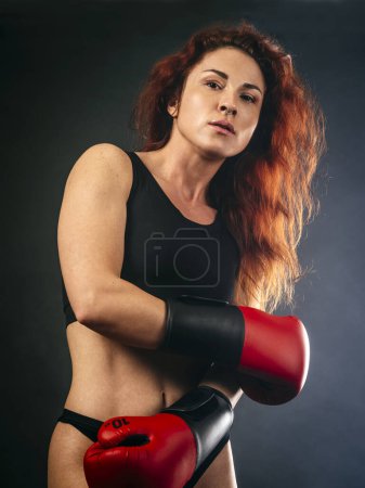 Photo for Beautiful woman with long red hair wearing boxing gloves and sportswear. - Royalty Free Image