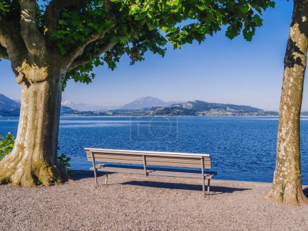 Photo for Empty bench on the edge of the lake in the old section of Zug, a beautiful city in Switzerland - Royalty Free Image