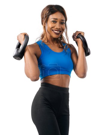 Photo for Woman of African descent doing bicep curls with kettlebell over white background. - Royalty Free Image
