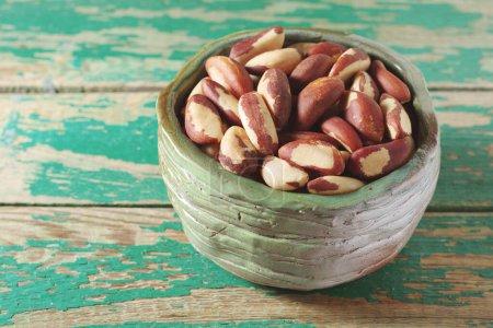 Brazilian nuts in bowl against old green wooden background