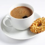 Cup of coffee and cookie rings with nuts on a white background