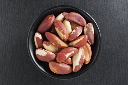 High angle view of brazil nuts in bowl on black stone background